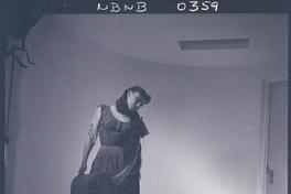 [Bailarina de ballet, caracterizada para una obra, posando de pié en una posición de movimiento]