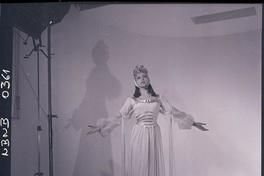 [Bailarina de ballet, caracterizada para una obra, posando de pié con los brazos extendidos]