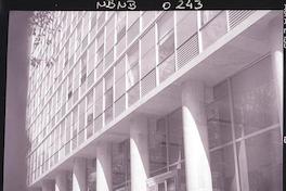 [Dos señoras acompañadas de un caballero, en el frontis de un gran edificio]