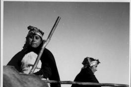 [Dos mujeres mapuches transportando sacos en una carreta]