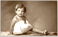 [Niñita rubia sentada de lado con las piernas cruzadas, vestido de dos colores y chalas blancas]