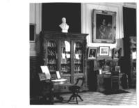 [Biblioteca Nacional. Sala José Toribio Medina, sala del Conservador, se divisan estanterías, un escritorio y cuadros]