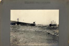 [Vista del muelle desde la playa, se divisan gruas y un barco]
