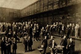 [Fotomontaje de un retrato colectivo: Un grupo de hombres, se encuentran al interior de la (biblioteca del Instituto Nacional), se observan mesas, estanterías y sillas, sentado a la extrema derecha, Diego Barros Arana]