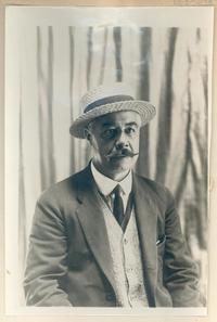 [Hombre sentado, con sombrero y bigote]