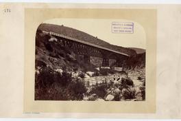 [Puente de gran magnitud entre cerros, a los pies hay un río donde se divisan dos personas]