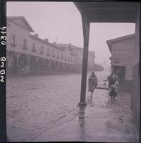 [Señoras caminando en un día de lluvia por una calle de Lota]