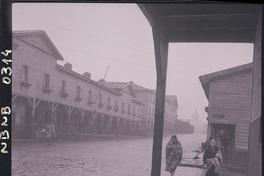 [Señoras caminando en un día de lluvia por una calle de Lota]