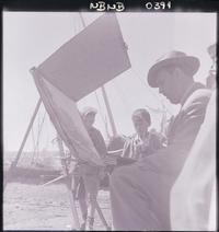 [Niños observan a Arturo Pacheco Altamirano, mientras pinta paisajes en la caleta de Angelmó]