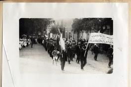 [Desfile patriótico en Arica, lo manifestantes llevan una bandera como estandarte y una pancarta]